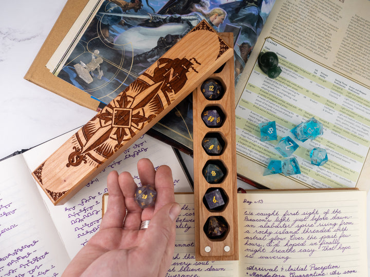 Wooden dice holder with engraved design on a table with game books and dice.