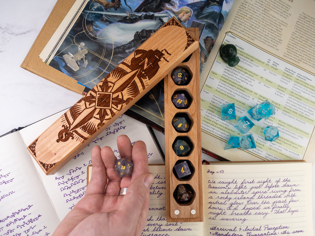 Wooden dice holder with engraved design on a table with game books and dice.