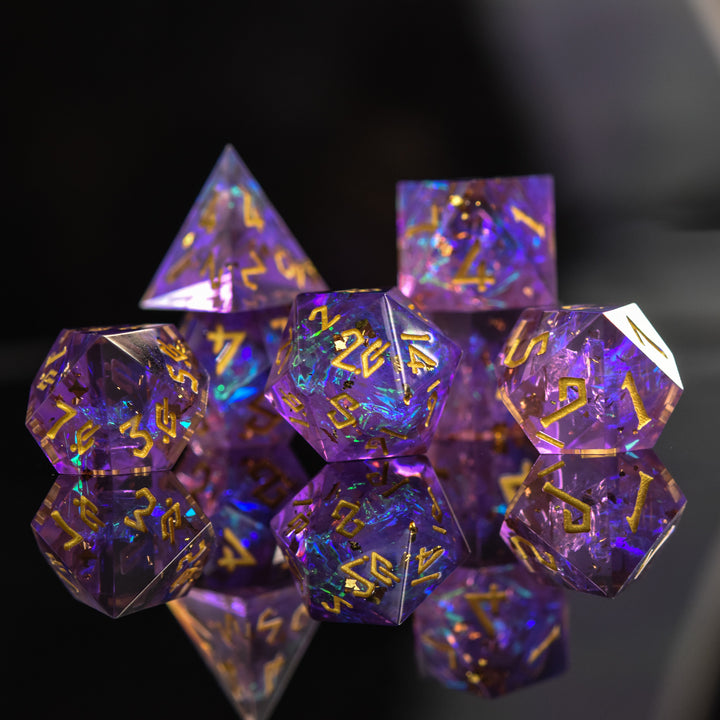 A set of sharp-edged, purple iridescent resin dice with engraved gold numbers, displaying a reflective surface.