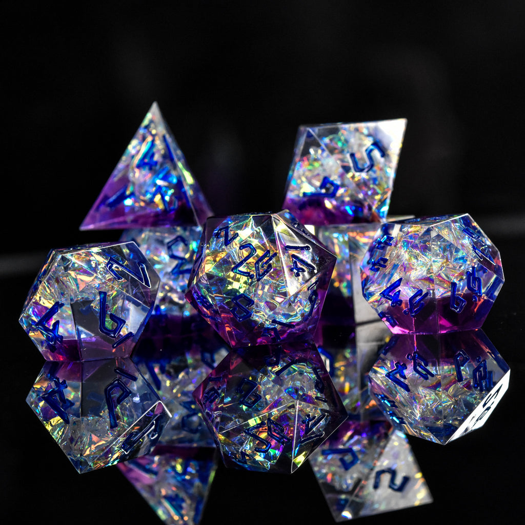 A set of sharp-edged, iridescent purple resin dice with hand-painted blue numbers, reflecting light and displaying a shiny surface.