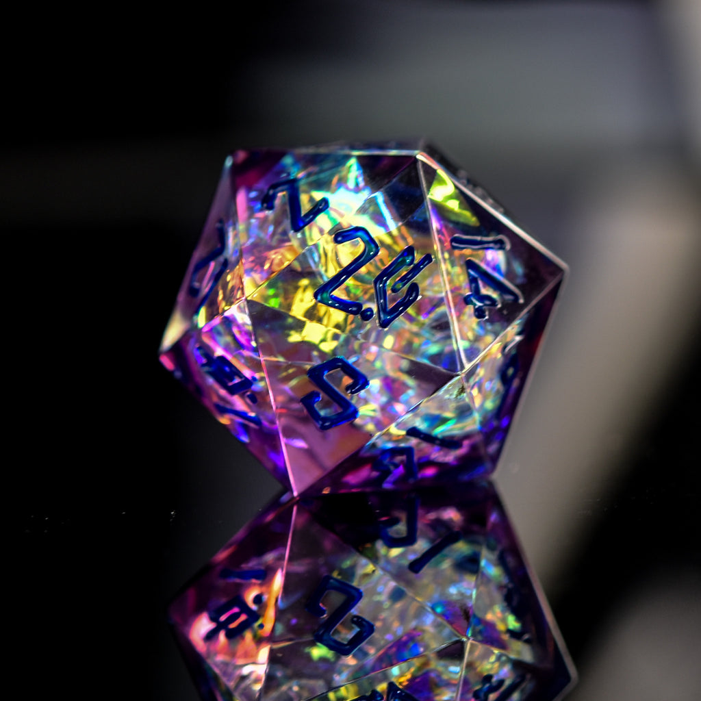 A set of sharp-edged, iridescent purple resin dice with hand-painted blue numbers, reflecting light and displaying a shiny surface.