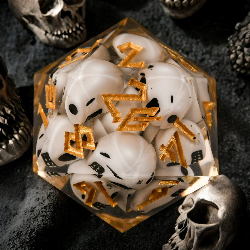 A clear resin dice filled with skulls with gold numbers, surrounded by small decorative skulls.
