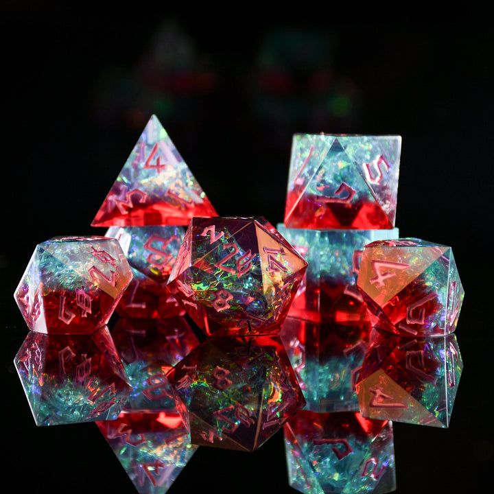 A set of sharp-edged, multicolored resin dice with hand-painted numbers, reflecting on a surface with a colorful backdrop.