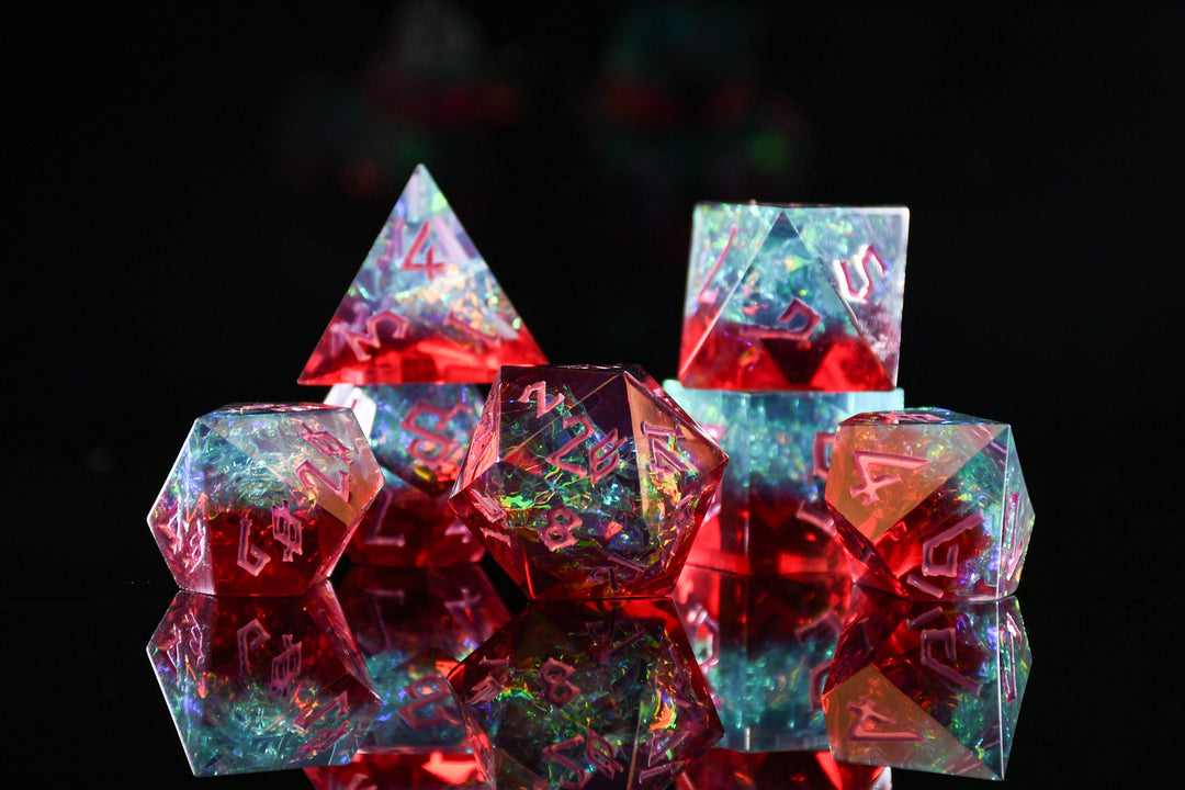 A set of sharp-edged, multicolored resin dice with hand-painted numbers, reflecting on a surface with a colorful backdrop.