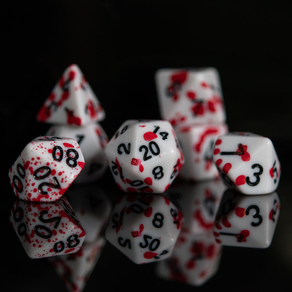 A set of acrylic dice with red numbers and accents on a white background, displayed on a reflective surface.