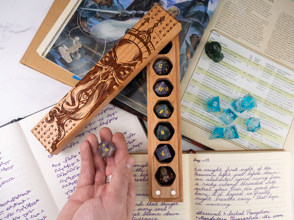 Wooden dice holder with engraved design on a table with game books and dice.