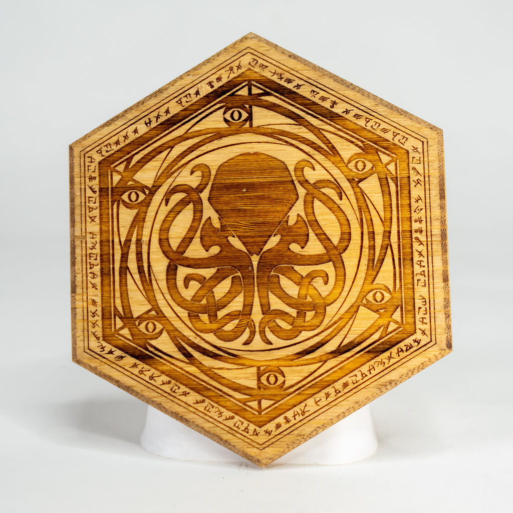 A decorative, polished wooden puck piece with engraved ctuhulu, used as a Dungeon Master screen accessory.