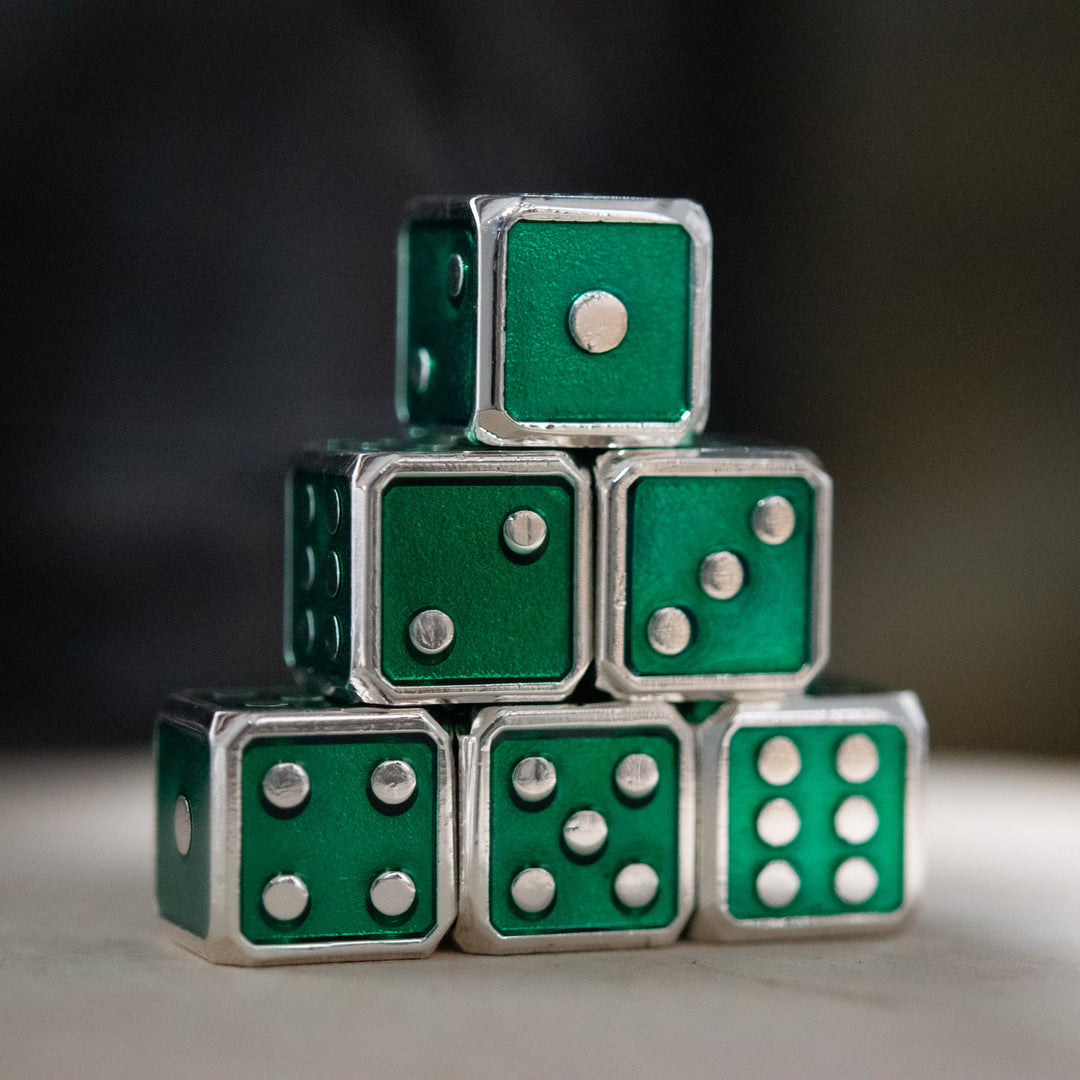 A stack of six green metal d6 dice with silver pips, arranged to form a pyramid shape.