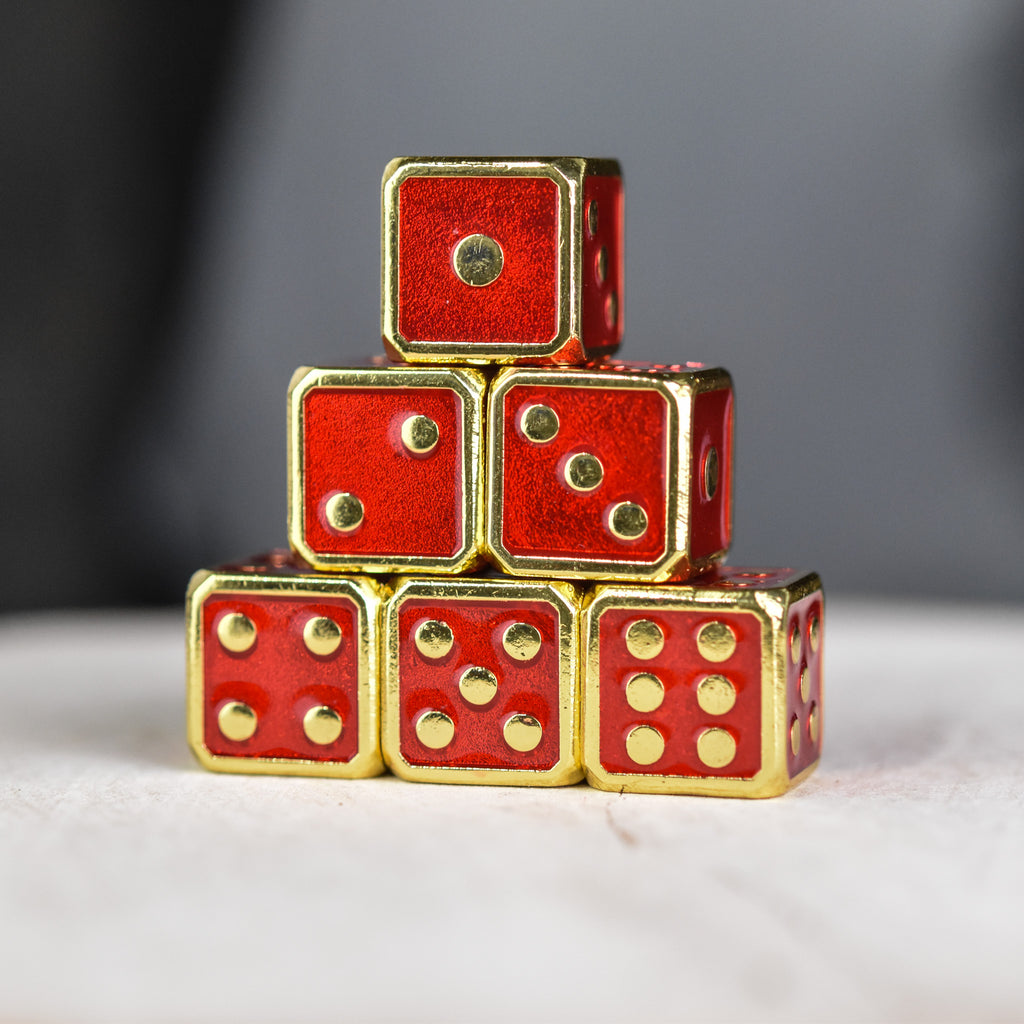 A pyramid stack of six red metal d6 dice with embossed gold pips.