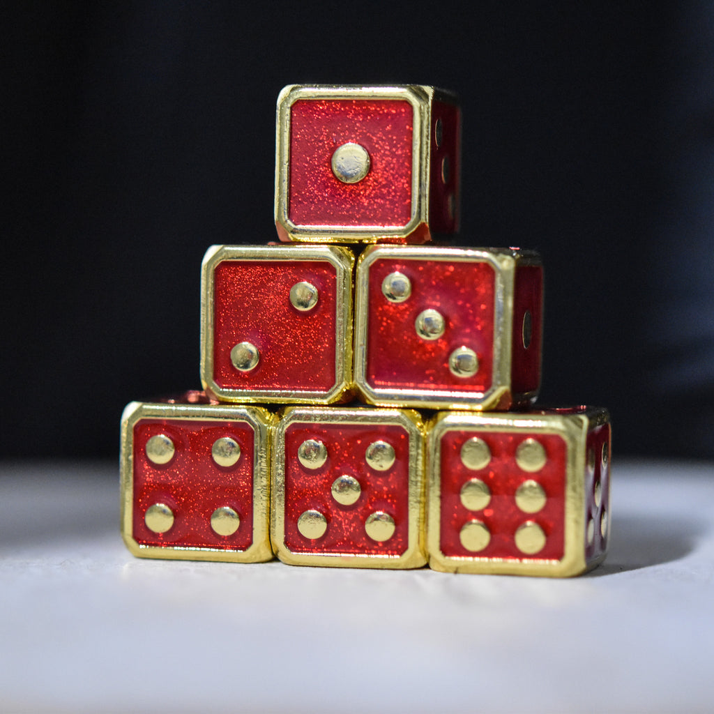 A pyramid stack of six red metal d6 dice with embossed gold pips.