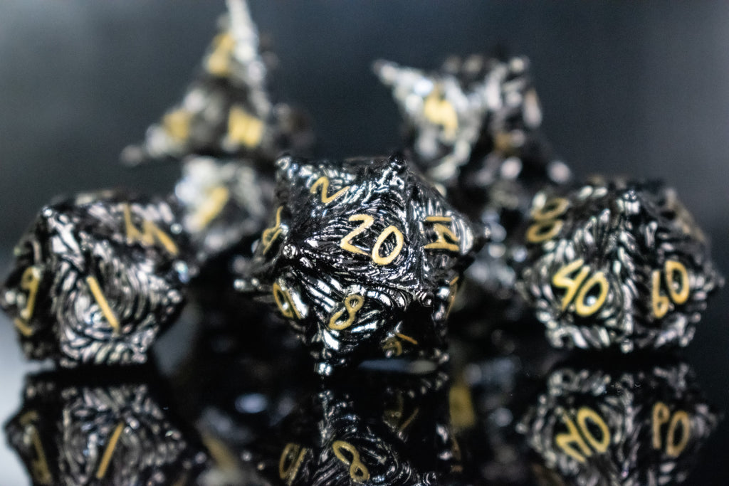 Black metal dice with vortex swirls and a gold font