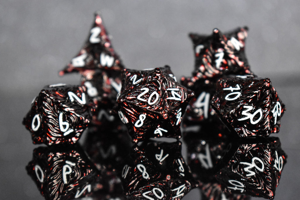 Deep red metal dice with vortex swirls and a white font