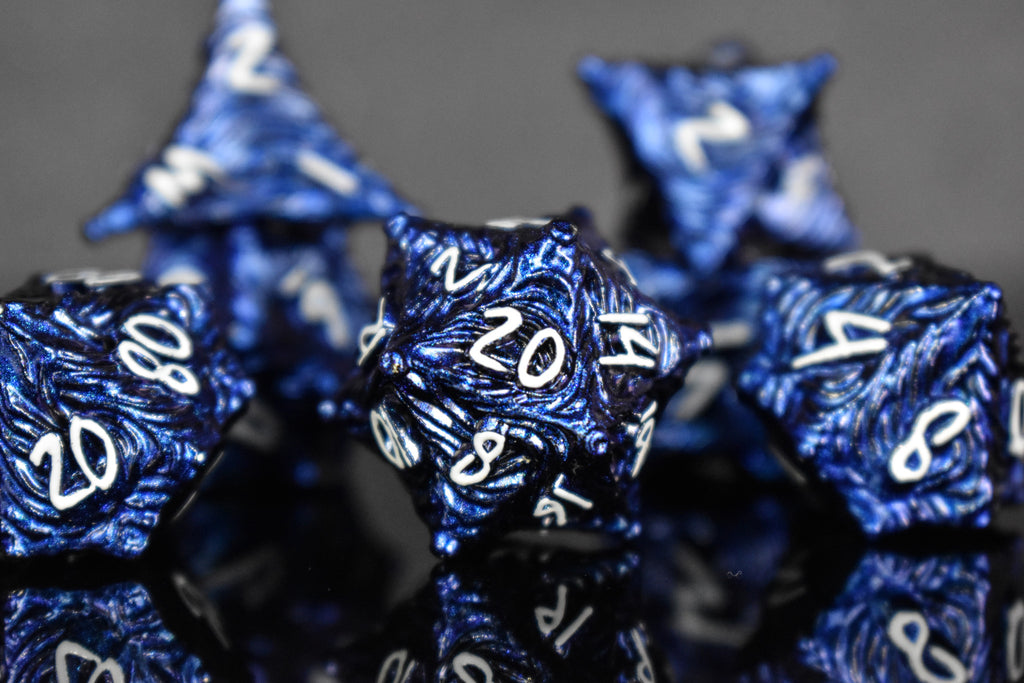 Dark blue metal dice with vortex swirls and a white font