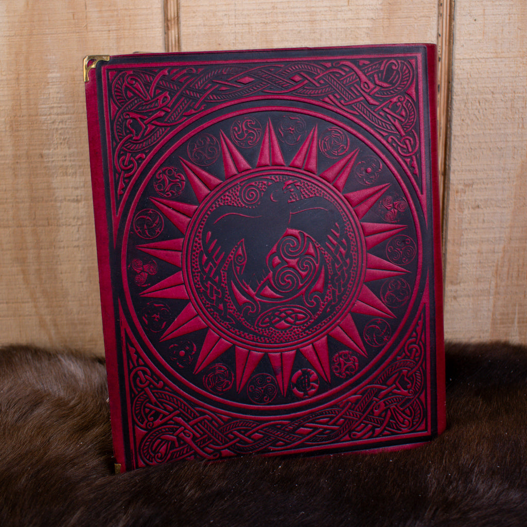 The back of a large red leather spell book journal featuring a raven within a sun