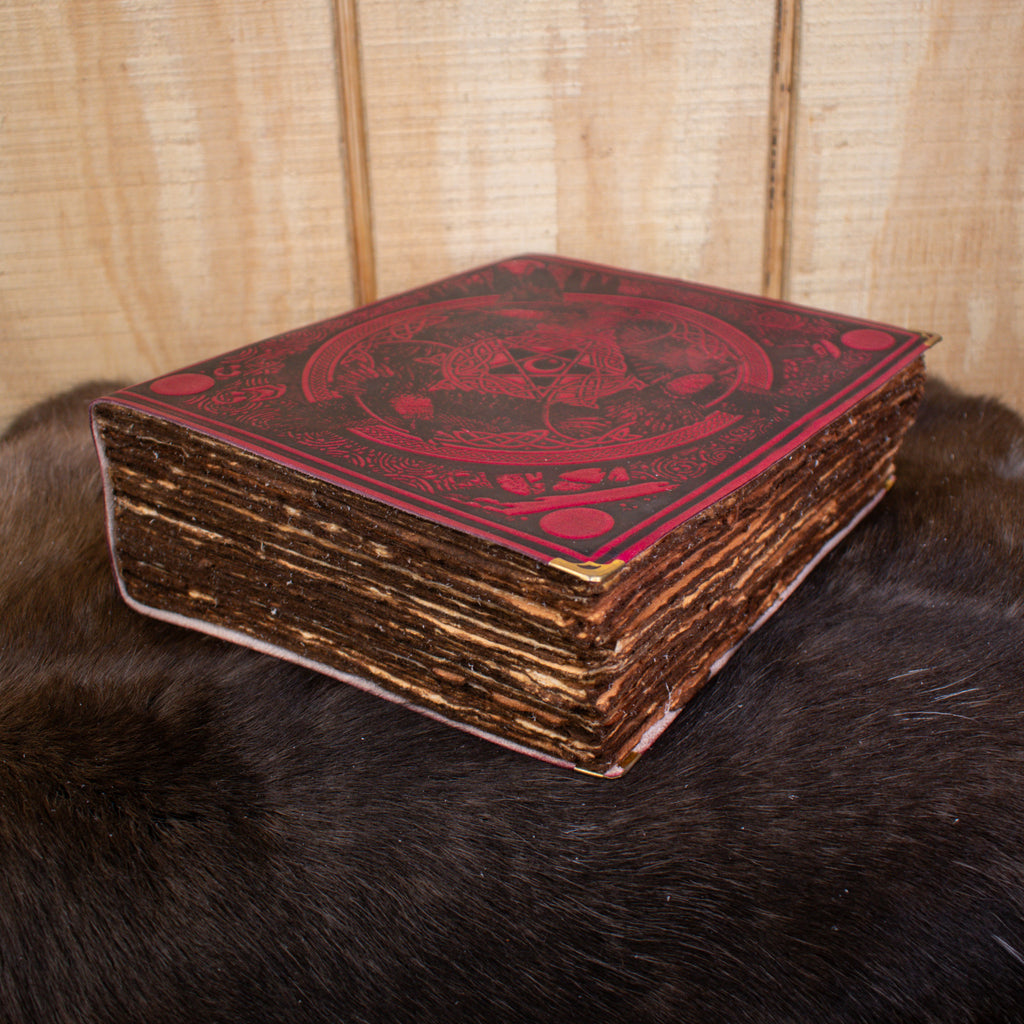 A large red leather spell book journal featuring ravens and a pentacle