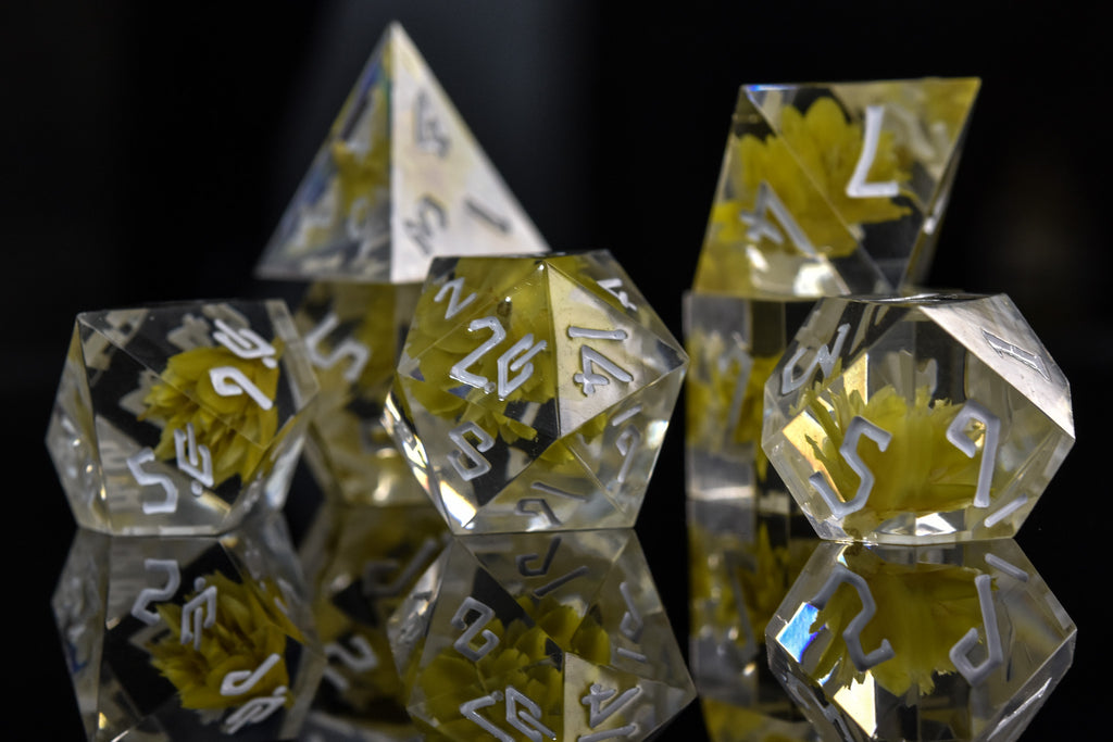 A dice set with real yellow flowers inside of clear sharp resin featuring white numbers in a Nordic font