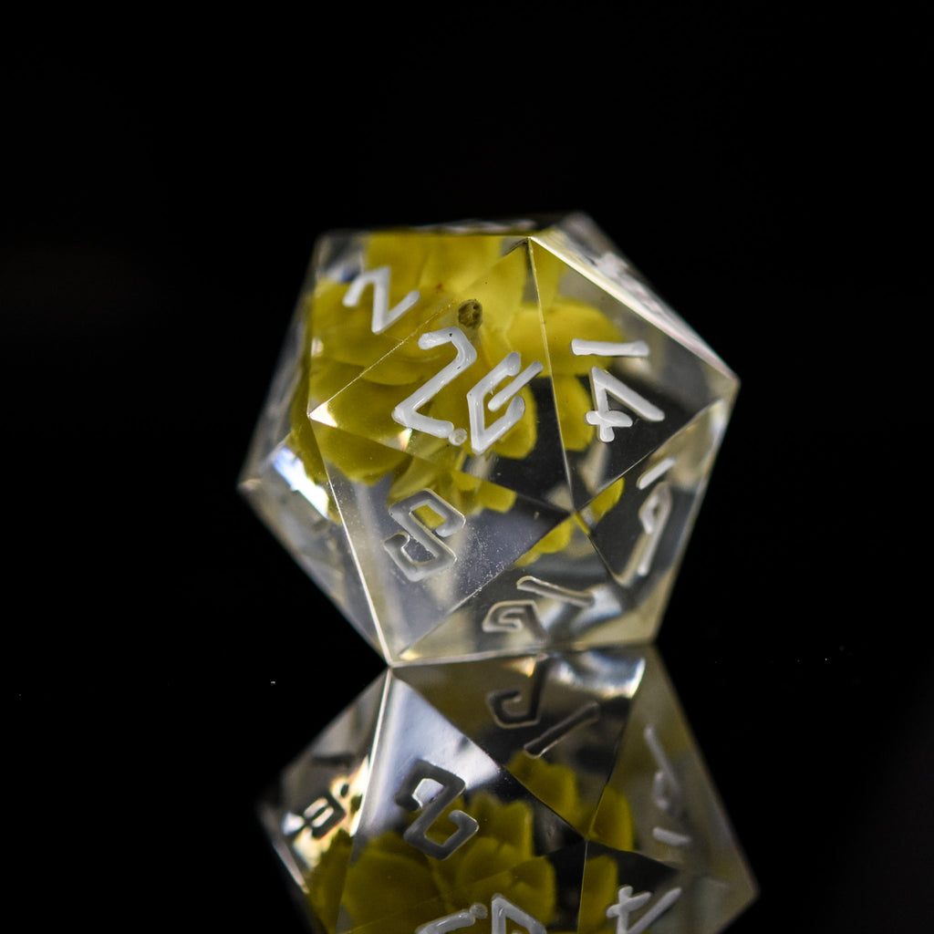 A D20 with real yellow flowers inside of clear sharp resin featuring white numbers in a Nordic font