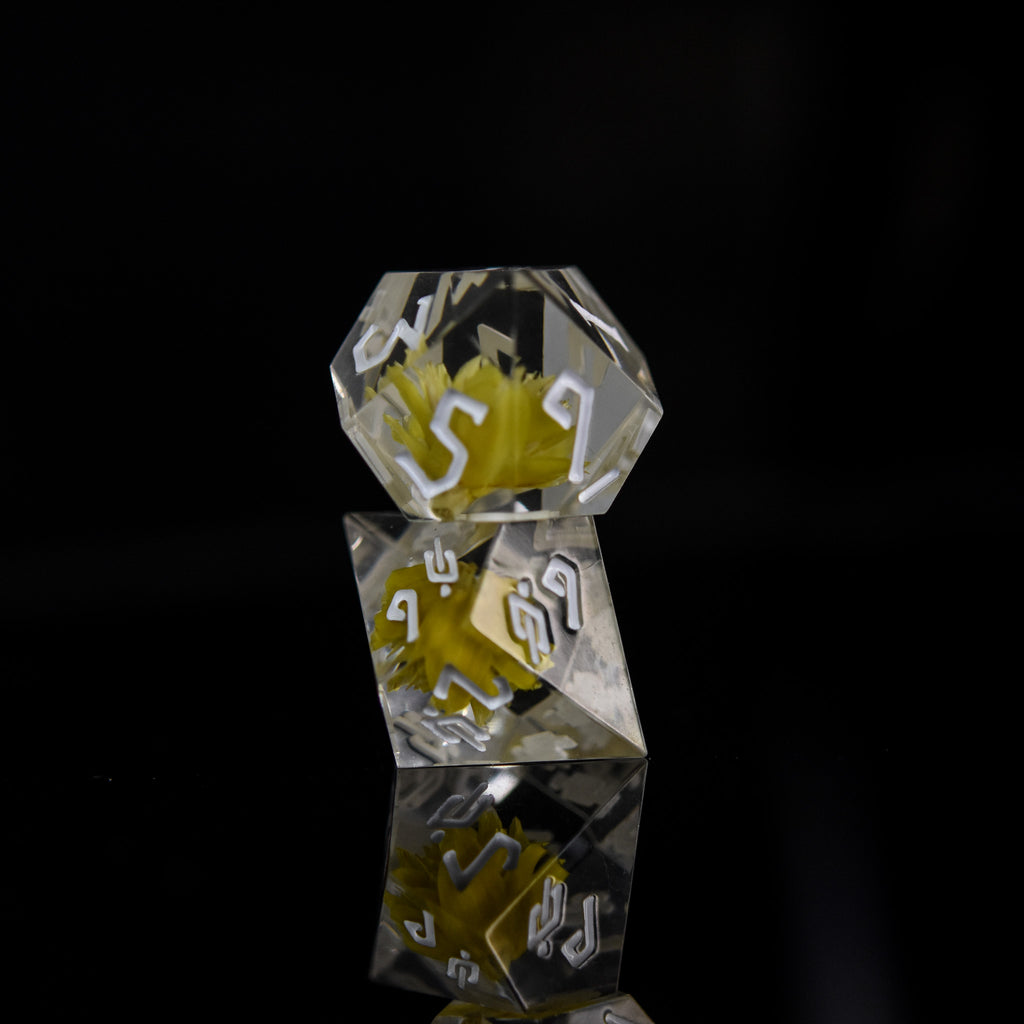 Dice with real yellow flowers inside of clear sharp resin featuring white numbers in a Nordic font