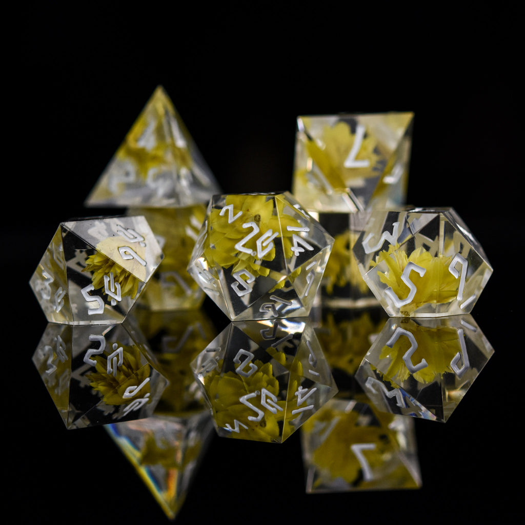 A dice set with real yellow flowers inside of clear sharp resin featuring white numbers in a Nordic font