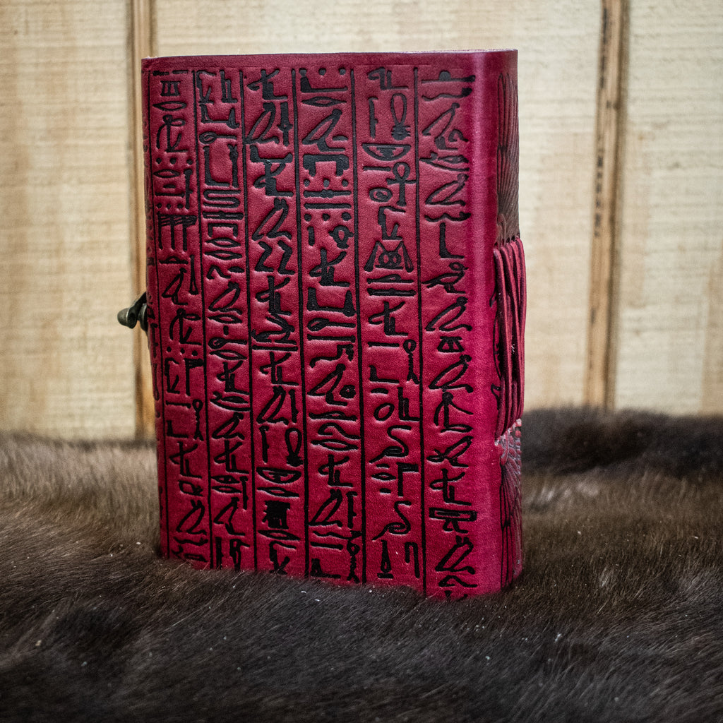 A red leather journal featuring hieroglyphics