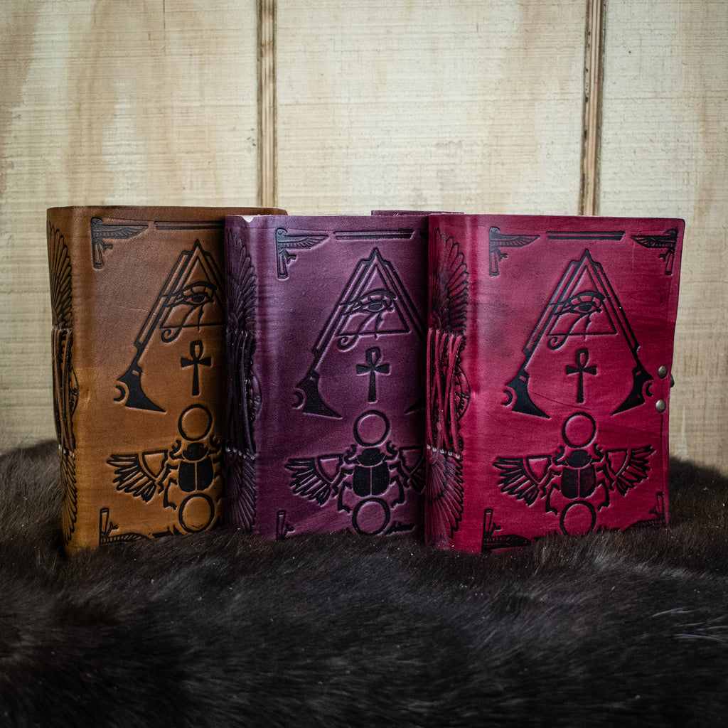 Three leather journals featuring hieroglyphics in tan, purple, and red