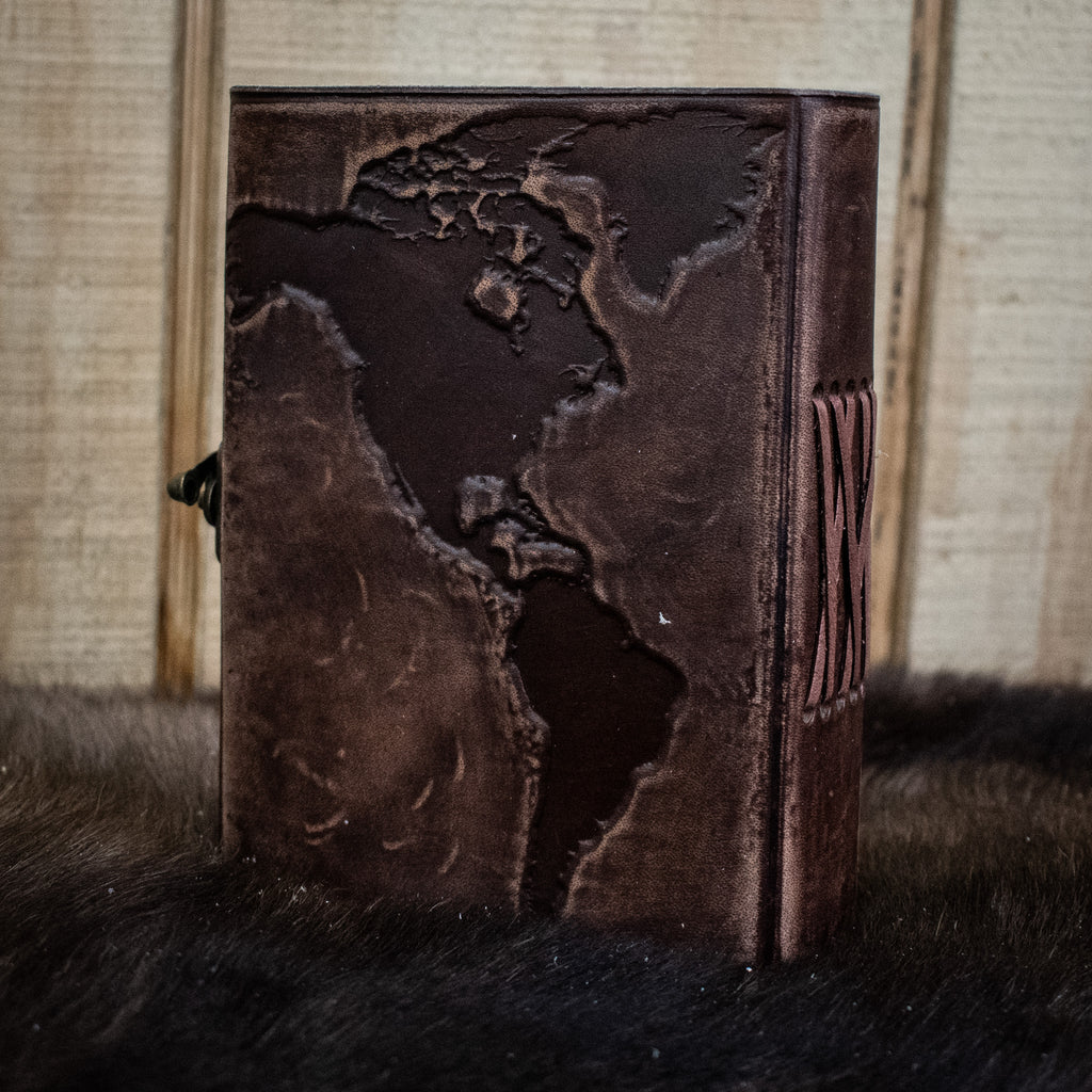 A dark brown leather journal featuring the world map