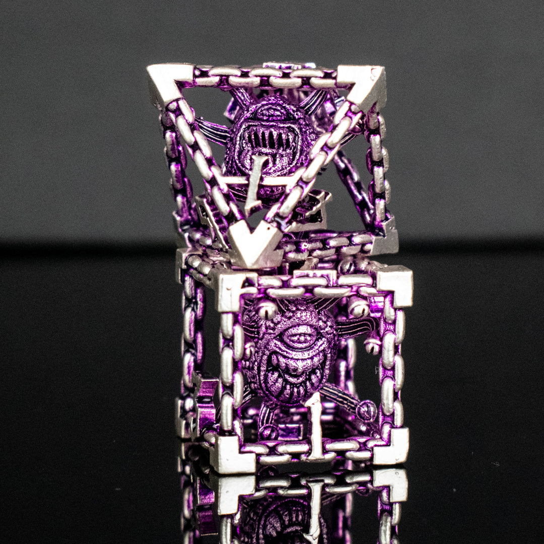 A set of hollow metal dice in purple and silver colors with embossed numbers and a beholder inside, reflecting on a shiny surface.