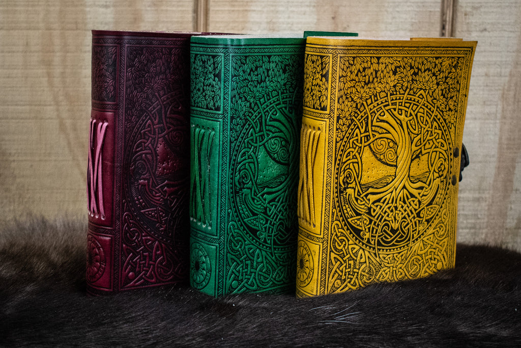 Three leather journals featuring the tree of life in red, green, and yellow
