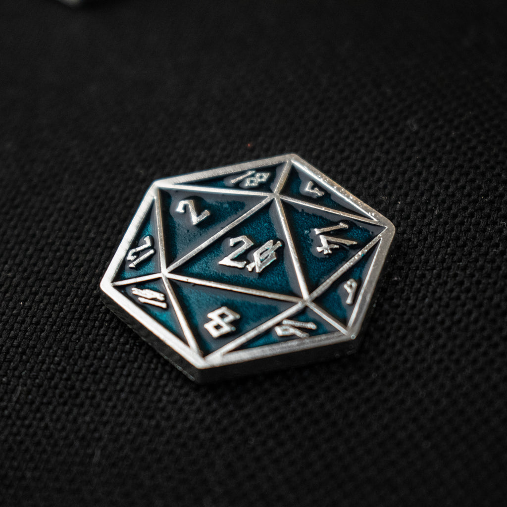 An aqua D20 pin with silver numbers in a Nordic font