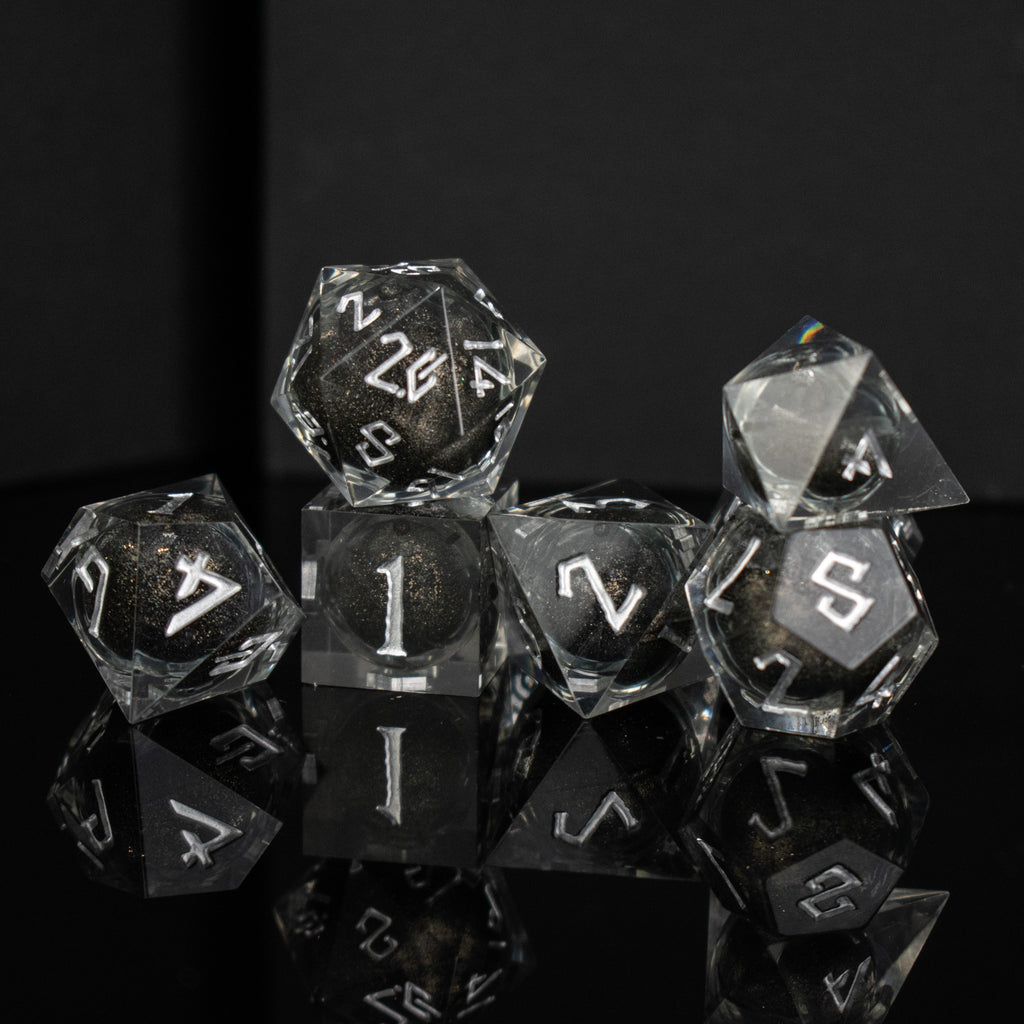 Black liquid and glitter inside of clear sharp resin dice with white numbers in a Nordic font