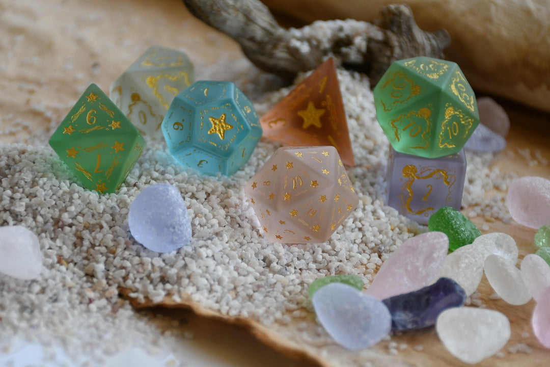 Colorful polyhedral dice on a sandy surface with driftwood
