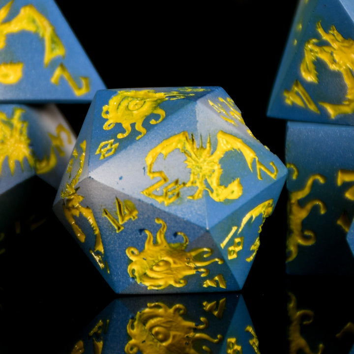 Blue polyhedral dice with yellow dragon designs on a reflective surface