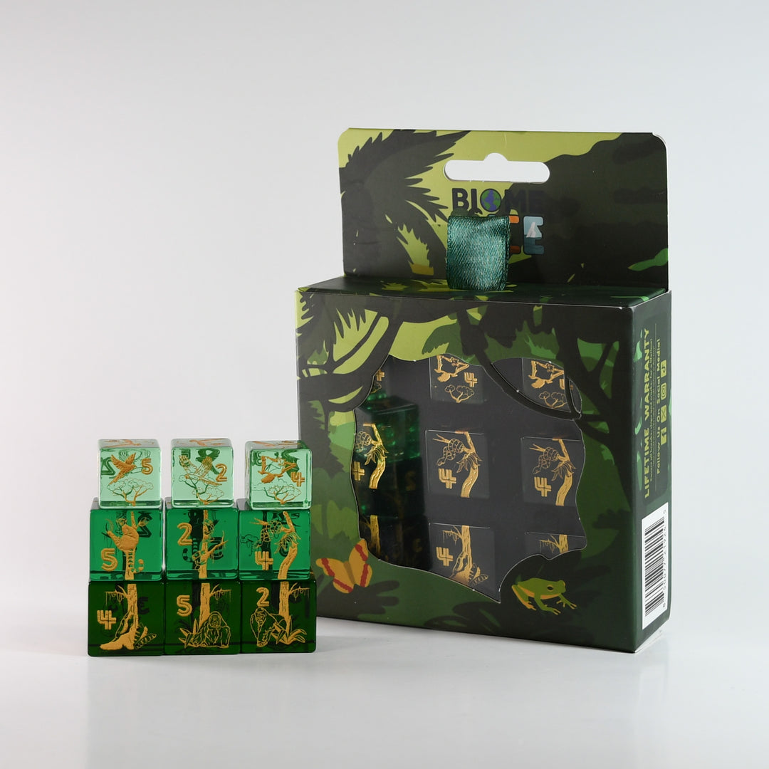 Set of green dice with gold numbers and symbols, displayed in front of their packaging.
