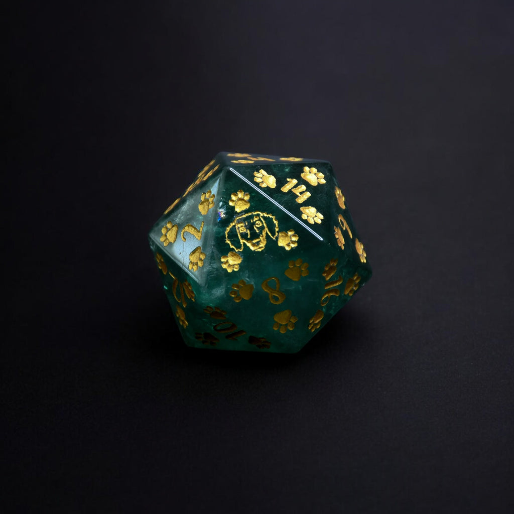 A Dachshund Puppy Paws Green Fluorite 30mm D20 with gold paint details, shaped as a D20, displayed on a natural stone surface.