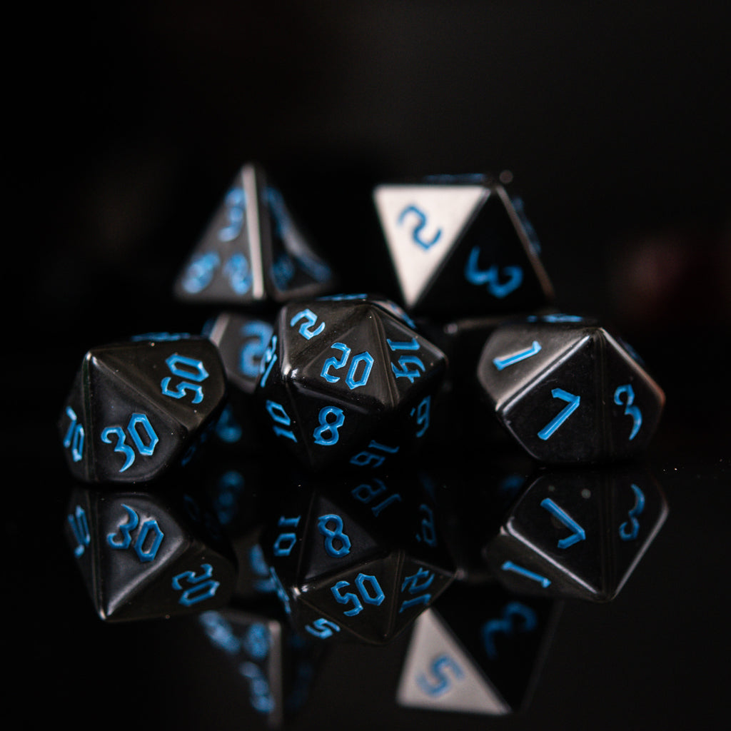 A set of black acrylic dice with blue gothic style numbers, including various shapes typical for role-playing games.