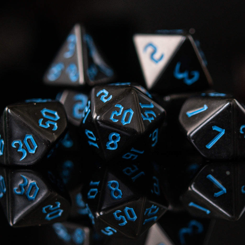 A set of black acrylic dice with blue gothic style numbers, including various shapes typical for role-playing games.