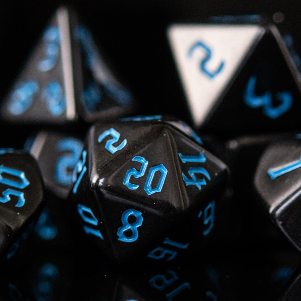 A set of black acrylic dice with blue gothic style numbers, including various shapes typical for role-playing games.
