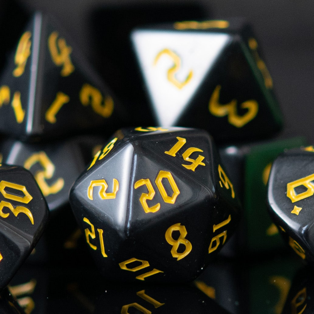 A set of black acrylic dice with yellow numbers, including various shapes typical for role-playing games.