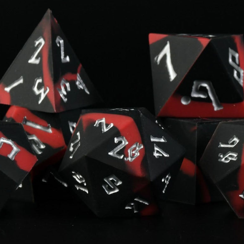 A set of silicone dice in black and red with white engravings, including various shapes such as a d4, d6, d8, d10, d12, and d20.