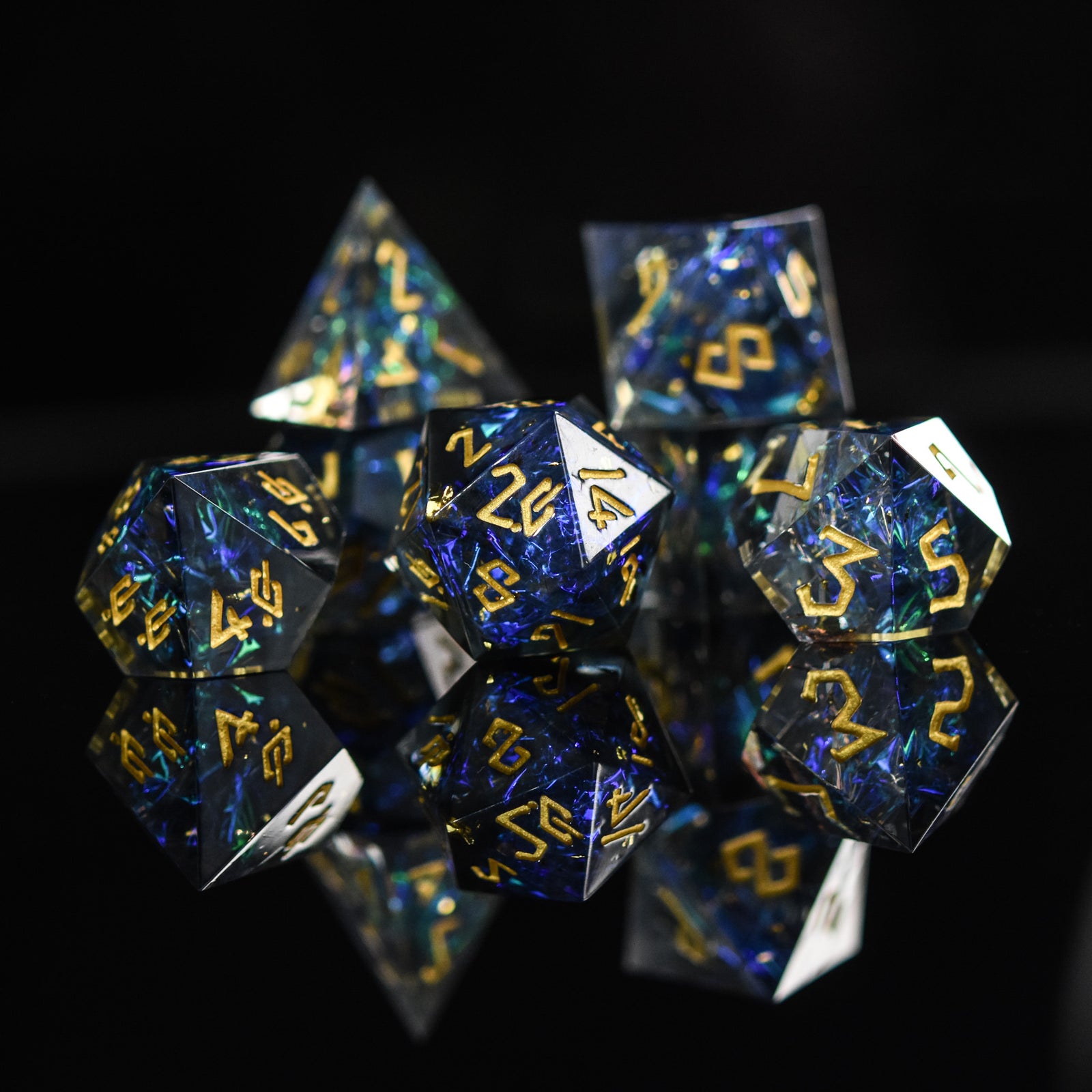 A set of sharp-edged resin dnd dice with blue and green metallic foil inside and gold numbering for tabletop gaming dungeons and dragons and board games