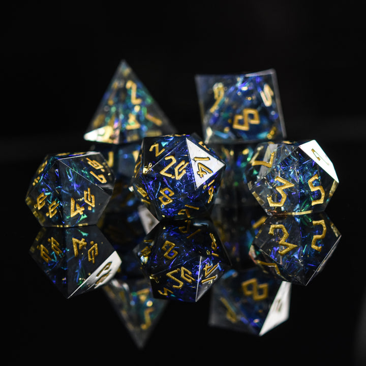 A set of sharp-edged resin dnd dice with blue and green metallic foil inside and gold numbering for tabletop gaming dungeons and dragons and board games