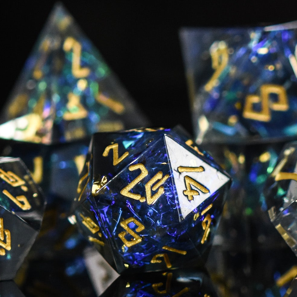 A set of sharp-edged resin dnd dice with blue and green metallic foil inside and gold numbering for tabletop gaming dungeons and dragons and board games
