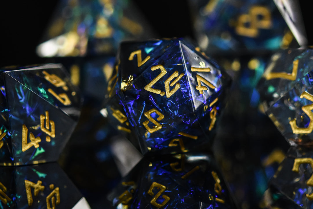 A set of sharp-edged resin dnd dice with blue and green metallic foil inside and gold numbering for tabletop gaming dungeons and dragons and board games