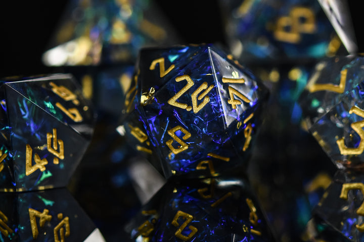 A set of sharp-edged resin dnd dice with blue and green metallic foil inside and gold numbering for tabletop gaming dungeons and dragons and board games