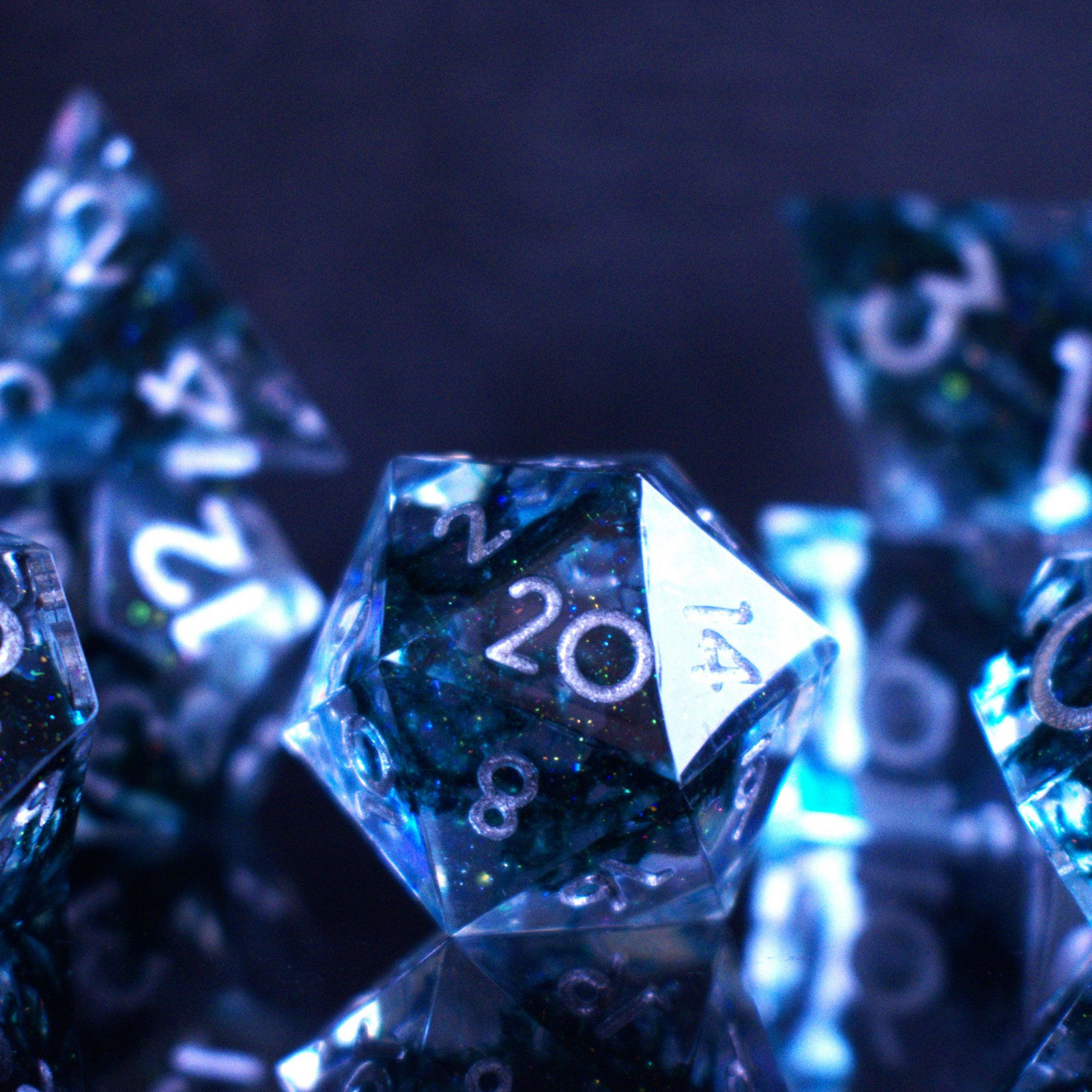 A set of sharp-edged resin dnd dice in blue with silver numbers and black and glitter details inside for ttrpg and board games