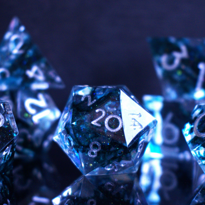 A set of sharp-edged resin dnd dice in blue with silver numbers and black and glitter details inside for ttrpg and board games