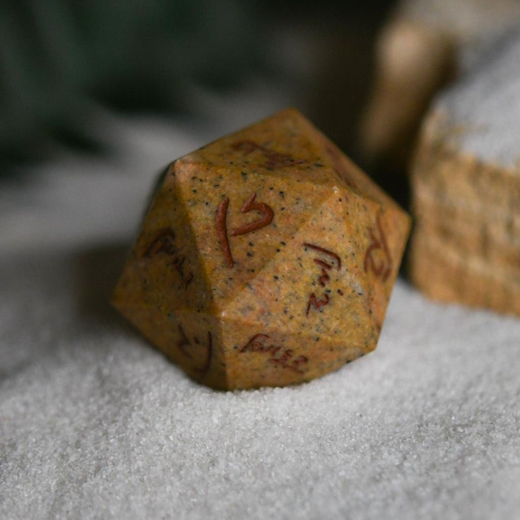 An oversized, inscribed limestone twenty-sided die, featuring Demotic script, displayed on a soft surface.
