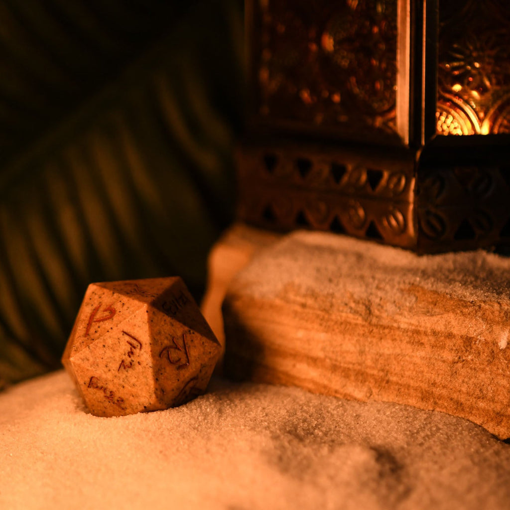 An oversized, inscribed limestone twenty-sided die, featuring Demotic script, displayed on a soft surface.