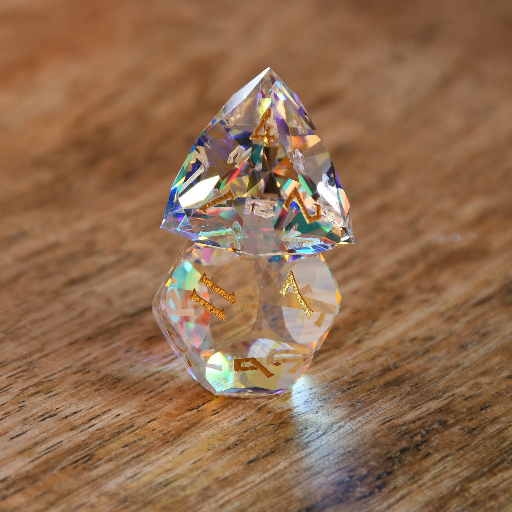 A close-up of a multifaceted, multicolored glass dice with engraved numbers, on a dark background.