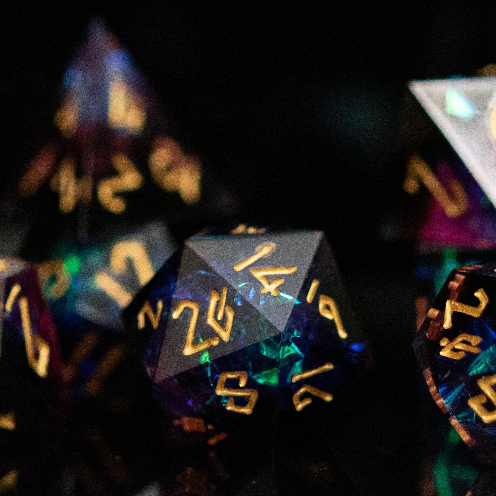a set of dark sharp edge resin polyhedral dnd dice with iridescent foil inside and gold numbering. 